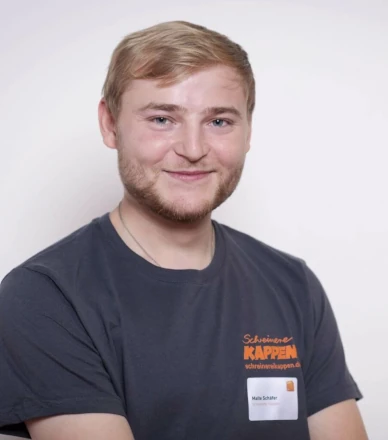 Junger Mann mit kurzem blondem Haar trägt ein T-Shirt mit Firmenlogo und Namensschild.